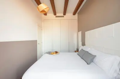 a bedroom with a large white bed with a ceiling at Aspasios Market Balconies Apartments in Barcelona