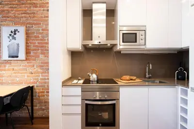 a kitchen with white cabinets and a brick wall at Aspasios Market Balconies Apartments in Barcelona