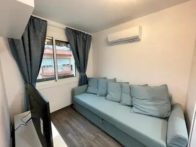 a living room with a blue couch and a window at Sant Adria Beach apartment Wi-Fi Parking Free in Sant Adria de Besos