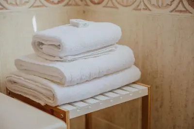 a stack of white towels on a shelf in a bathroom at Collbato Resort. in Collbató