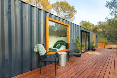 a house with a deck with a bed and a mirror at Cabaña del Bosque in Canyelles
