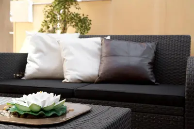 a black couch with pillows and a white flower on a table at Casa Maca Guest House in Barcelona