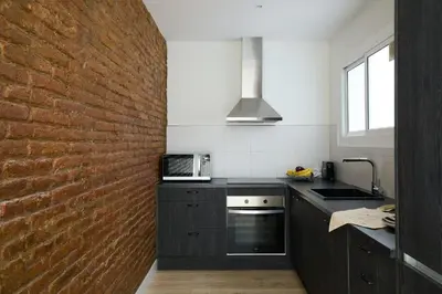 a kitchen with a brick wall and a sink and a microwave at Casa Cosi - Casanova 3 in Barcelona