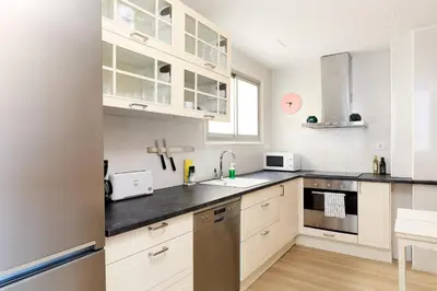 a kitchen with white cabinets and black counter tops at Casa Cosi - Casanova 6 in Barcelona
