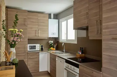 a kitchen with wooden cabinets and a white microwave at Casa Cosi - Casanova 1 in Barcelona