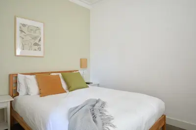 a bedroom with a white bed with orange and green pillows at Casa Cosi - Francoli 4 in Barcelona
