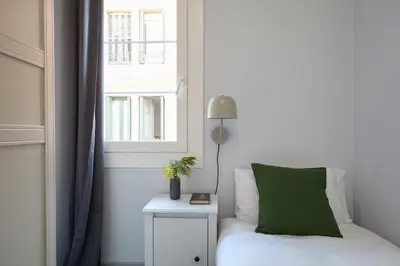 a bedroom with a bed with a green pillow and a window at Casa Cosi - El Farro 2 in Barcelona