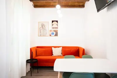 an orange couch in a white room with a table at Casa Cosi - La Gleva 3 in Barcelona