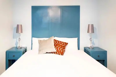 a bedroom with a large bed with two blue night stands at Casa Cosi - La Gleva 3 in Barcelona
