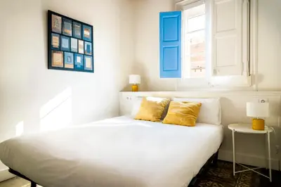 a white bed with two yellow pillows in a bedroom at Casa Cosi - La Gleva 4 in Barcelona
