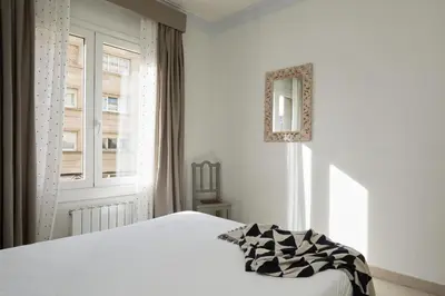 a white bedroom with a bed and a window at Casa Cosi - Casanova 4 in Barcelona