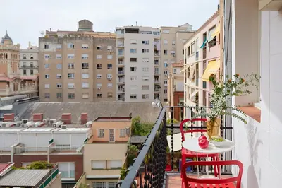 a balcony with a red table and chairs and buildings at Casa Cosi - El Farro 1 in Barcelona