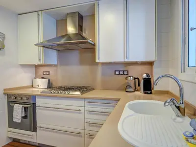a kitchen with white cabinets and a stove and a sink at Balmins Surf by Hello Homes Sitges in Sitges