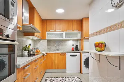 a kitchen with white appliances and wooden cabinets at Love Local Life Near Sagrada Familia by MyRentalHost in Barcelona