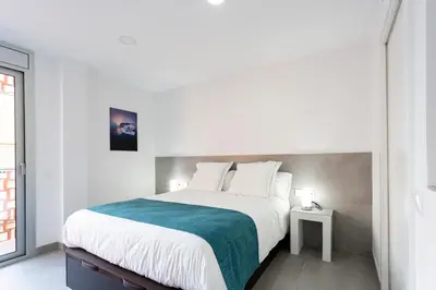 a white bedroom with a large bed and a window at 8 lacus BAIKAL in Hospitalet de Llobregat