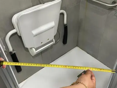 a person holding a yellow ruler in a bathroom stall at 8 lacus VICTORIA in Hospitalet de Llobregat