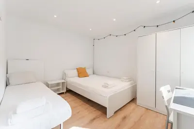a white room with two beds and a table at Feel Welcome Barcelona Smart flat in Cornellà de Llobregat