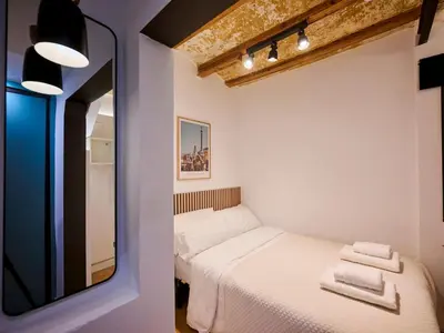 a small bedroom with a bed and a mirror at Casa Wilson by MyRentalHost in Barcelona