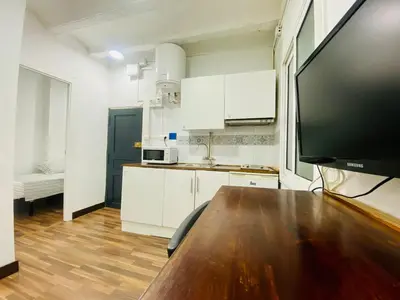 a kitchen with a wooden table and a large screen tv at 08 Apartament lof 3 2 in Barcelona