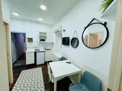 a small white kitchen with a mirror and a table at 08 Apartament lof 3 2 in Barcelona