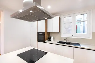 a kitchen with white cabinets and a stainless steel hood at Majestic 4BR/4BATH apartment in Sagrada Familia area in Barcelona