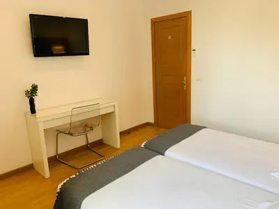 a bedroom with a bed and a desk and a television at Super Balmes Guest House in Barcelona