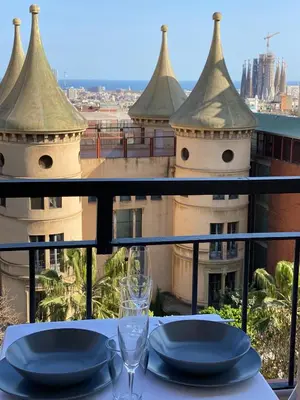 a table with plates and glasses on a balcony at Amazing sea and Sagrada Familia views homey apartment in Barcelona
