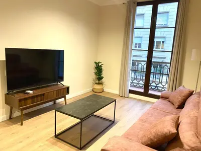 a living room with a couch and a flat screen tv at Anais Apartments by gaiarooms in Barcelona