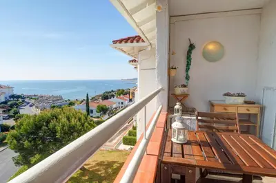 a balcony with a wooden bench and a view of the ocean at Seaside Cozy Apartment by Hello Homes Sitges in Sitges