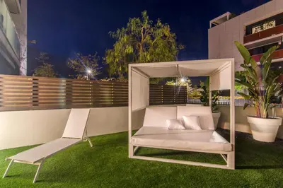 a white porch swing and a chair on a lawn at Sitges Spaces Garden Paradise 3 bedroom, 3 bathroom, huge PRIVATE garden-terrace, pool- sleeps up to 8 in Sitges