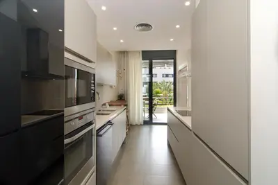 a kitchen with black appliances and white cabinets at Sitges Spaces Garden Paradise 3 bedroom, 3 bathroom, huge PRIVATE garden-terrace, pool- sleeps up to 8 in Sitges
