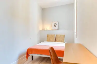 a small bedroom with a bed and a wooden table at Bright 2bdr In Trendy Gracia in Barcelona