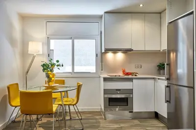 a small kitchen with a table and yellow chairs at BBarcelona Sant Pau Flat in Barcelona
