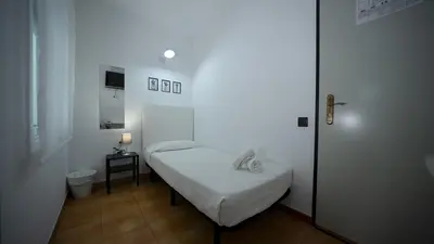 a small white room with a bed and a telephone at Hostal La Premsa in Arenys de Mar