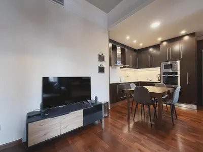 a living room with a table and a tv and a kitchen at Stay U-nique Apartments Industria II in Barcelona