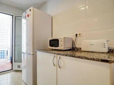 a kitchen with a white refrigerator and a microwave at Molins Apartment by Hello Homes Sitges in Sitges