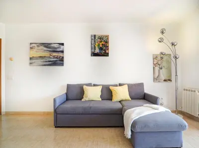 a living room with a blue couch and some paintings at Molins Apartment by Hello Homes Sitges in Sitges