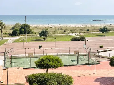 a tennis court in front of the beach at Onze - primera línea de mar con piscina in Cubelles