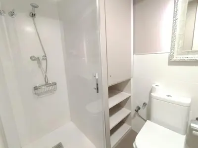 a white bathroom with a toilet and a shower at Montserrat Apartments by gaiarooms in Barcelona