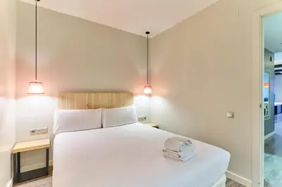 a bedroom with a large white bed with two lights at Montserrat Apartments by gaiarooms in Barcelona