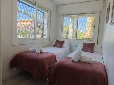 two beds in a room with two windows at Apartamento 2 habitaciones y magnífica terraza in Castelldefels