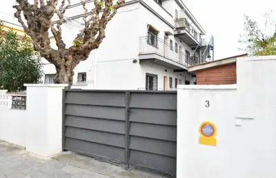 a white house with a black fence and a building at Apartamento 2 habitaciones y magnífica terraza in Castelldefels