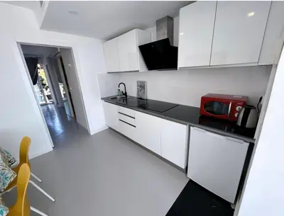 a kitchen with white cabinets and a red microwave at HUG HOTEL2022 in El Carrer del Canonge