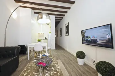 a living room with a couch and a tv on a wall at The White Flats Sant Antoni in Barcelona