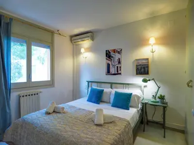 a bedroom with a bed with blue pillows and a window at Ocean Spirit House by Hello Homes Sitges in Sitges