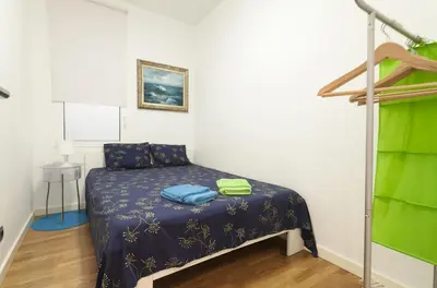 a small bedroom with a bed with a blue comforter at Key Gracia Apartments in Barcelona