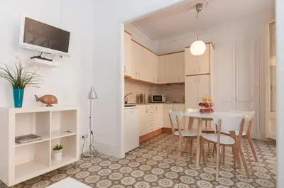 a kitchen with white cabinets and a table and chairs at Weflating Sant Antoni Market in Barcelona