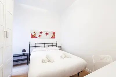 a white bedroom with a bed and a chair at Sagrada Familia LEPANT in Barcelona