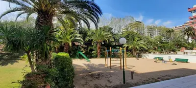 a playground in a park with palm trees and a swing at Bright with pool near the beach and Barcelona by train in Masnou