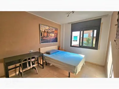 a bedroom with a bed and a desk and a window at Apartament Calella in Calella